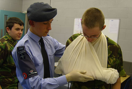 A cadet demonstrating making an arm sling